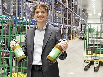 Lukas Nossol, Sohn des Firmengründers und Dennree-Marketingleiter, steht im Zentrallager in Töpen und hält zwei Flaschen mit Vollmilch der Hausmarke. Das Sortiment hier umfasst 13 000 Artikel. Foto: Matthias Litzlfelder