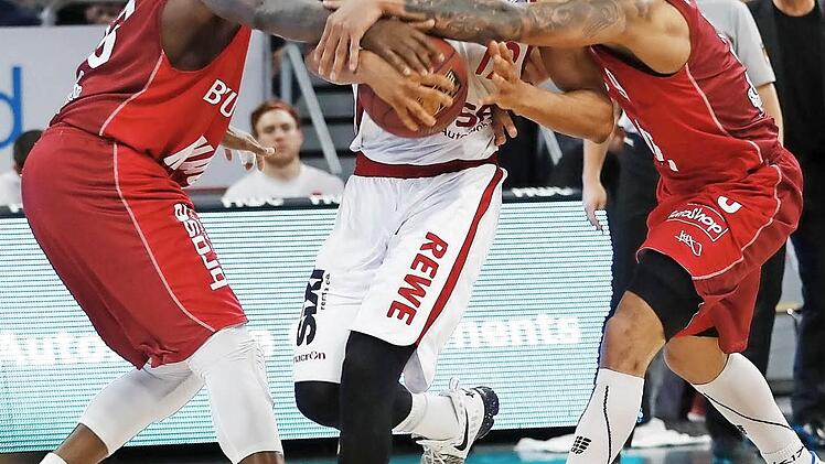Die Würzburger Marshawn Powell (l.) und Maurice Stuckey (r.) greifen dem Bamberger Aufbauspieler Maodo Lo in den Arm. Foto: Daniel Löb