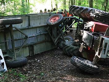 Das verunglückte Gespann: Auf der Seite blieben der Traktor und der Anhänger liegen. Die Ursache des Unfalls ist bisher nicht bekannt. Offenbar wurde die Hanglage dem Fahrer und den Ausflüglern zum Verhängnis.