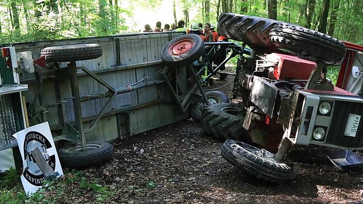 Das verunglückte Gespann: Auf der Seite blieben der Traktor und der Anhänger liegen. Die Ursache des Unfalls ist bisher nicht bekannt. Offenbar wurde die Hanglage dem Fahrer und den Ausflüglern zum Verhängnis.