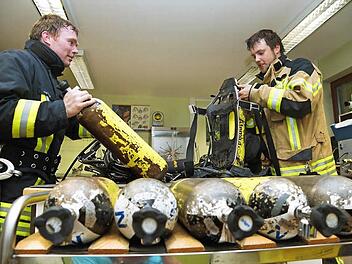 Zwei Feuerwehrmänner bauen ihre Pressluftflaschen aus.Fotos: Arkadius Guzy
