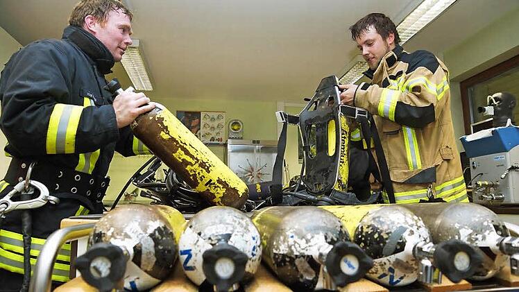 Zwei Feuerwehrmänner bauen ihre Pressluftflaschen aus.Fotos: Arkadius Guzy