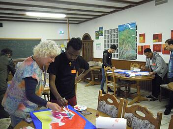 Helga Weißenberger zeigt einem jungen Flüchtling die richtige Maltechnik. Foto: Julia Raab