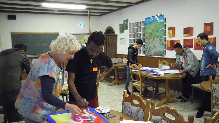 Helga Weißenberger zeigt einem jungen Flüchtling die richtige Maltechnik. Foto: Julia Raab