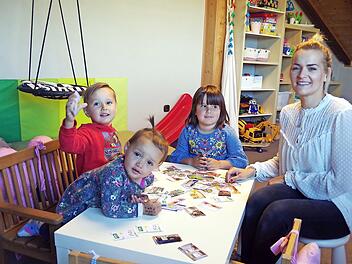 Ida, Michl und Anni Kolb (v. l.) spielen gemeinsam mit ihrer Mutter Katrin Kolb das Familien-Memory mit Motiven aus ihrer Kindertagesstätte St. Laurentius Neufang.  Fotos: Heike Schülein
