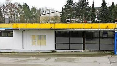 Seit dem Umzug in den neuen Edeka-Markt ist das Gebäude in Sandhof verwaist. Was bisher geschah? Das Tor zu einem Lagerraum wurde aufgebrochen, die Glascontainer auf Drängen des Eigentümers abgeholt.