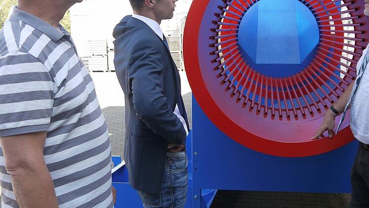 Ein bisschen auffallen darf schon sein: Die kräftigen Farben gehören bei der Brennholz-Reinigungstrommel dazu, erklären Norbert Dressel und Dominic Dressel dem Landrat, Michael Busch, bei der Führung durch das Außengelände des Metallbauspezialisten. Foto: Berthold Köhler