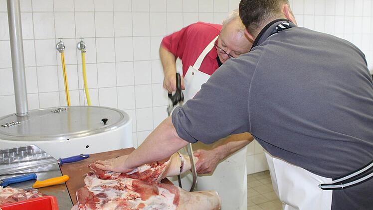 Walter Steinert und Mario Winkelmann (von links) zerlegen die Schweinekeule.
