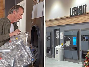 Ein Mann benutzt einen modernen Leergutautomaten, der viele Dosen und Flaschen gleichzeitig annimmt. Rechts im Bild sind weitere Automaten und ein Weihnachtsbaum zu sehen.