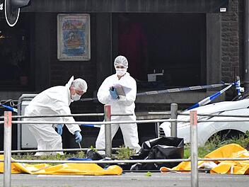 Polizisten untersuchen den Tatort, an dem zuvor Schüsse gefallen sind. Ein mutmaßlicher Terrorist hat nach offiziellen Angaben im belgischen Lüttich zwei Polizisten und einen Mann in einem Auto erschossen, bevor er selbst von Sicherheitskräften getötet wurde. Foto: Geert Vanden Wijngaert/AP/dpa