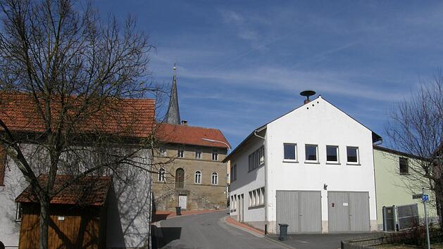 Der Dorfplatz Theinfeld mit Feuerwehrhaus (rechts) und die ehemalige Schule (Mitte). Philipp Bauernschubert