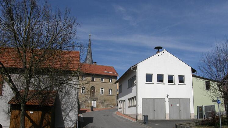 Der Dorfplatz Theinfeld mit Feuerwehrhaus (rechts) und die ehemalige Schule (Mitte). Philipp Bauernschubert