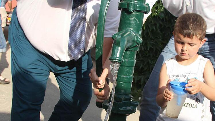 Emmanuel Kretter lässt Bernd Rehorz von der IHK und Bürgermeister Martin Bernreuther für sich Wasser pumpen.