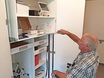Reinhard Wolf demonstriert, wie man auch vom Rollstuhl aus leicht an die oberen Regalfächer herankommt. Der Spezialschrank hat ein patentiertes System. Per Fernbedienung kann man den oberen Schrankteil absenken.