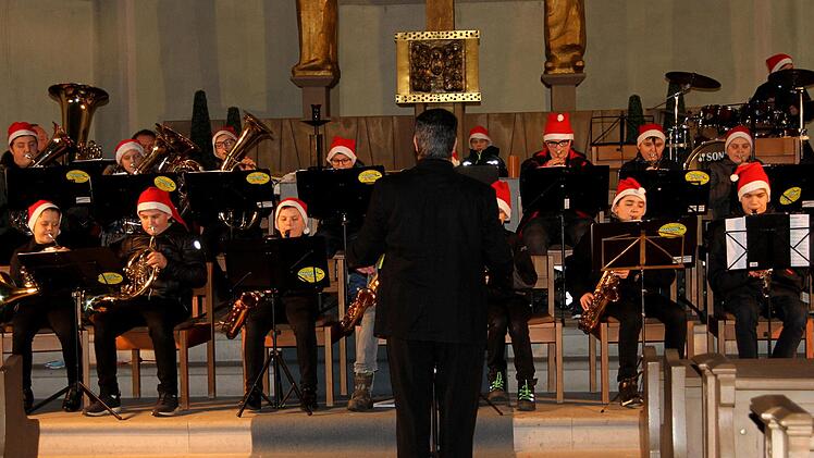 Ihre weihnachtlichen Weisen präsentierte das Jugendorchester mit Mützen kleiner Weihnachtsmänner, hier mit Dirigent Werner Lehrieder.