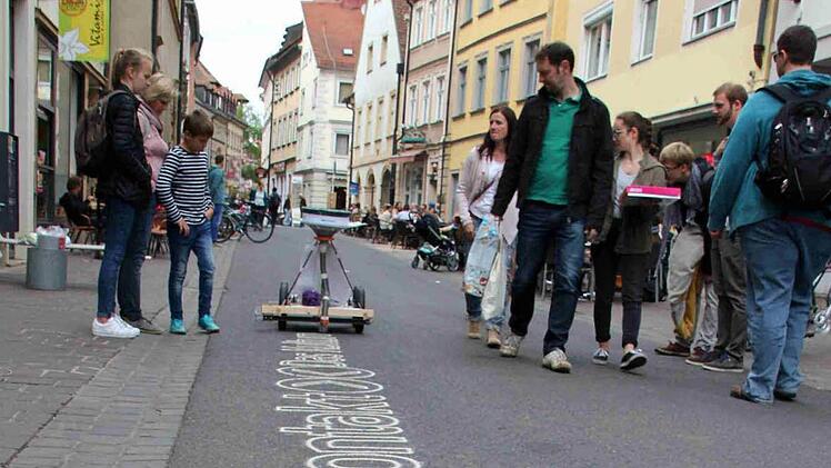 Was ist das denn? Der Sandschreiber zieht Blicke der Passanten in der Austraße auf sich und wirbt für "kontakt - Das Kulturfestival".  Foto: Sebastian Martin