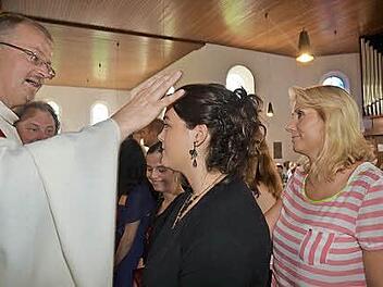 Regionaldekan Thomas Teuchgräber spendete in der Heilig-Kreuz-Kirche in Reitsch 41 Firmlingen das Sakrament der Firmung, hier Fabiana Schramm mit Firmpatin Carla Passador (rechts). Im Hintergrund Pater Waldemar Brysch. Foto: Karl-Heinz Hofmann