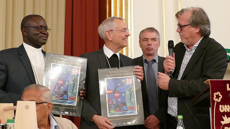 Erzbischof Ludwig Schick und Bischof André Guèye bekamen von Professor Gerhard Seitz die ersten Exemplare des neuen Kunstkalenders 2020 überreicht. Foto: Marion Krüger-Hundrup