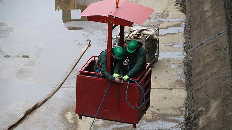 In einem Mannkorb, der am Kran hängt, schweben die Arbeirter über der Schleuse.  Foto: Andreas Schmitt