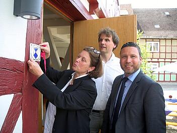 Ein Denkmal, das Zeichen setzt: Christine Bardin, Florian Kirfel und Martin FInzel (von links) heften dem "Markt 33" im Ummerstadt das Zeichen eines Baudenkmals an die hirstorische Fassade. Foto: Bettina Knauth