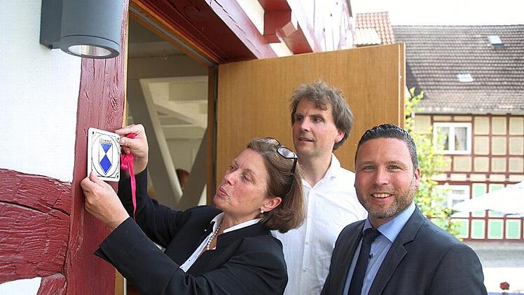Ein Denkmal, das Zeichen setzt: Christine Bardin, Florian Kirfel und Martin FInzel (von links) heften dem "Markt 33" im Ummerstadt das Zeichen eines Baudenkmals an die hirstorische Fassade. Foto: Bettina Knauth
