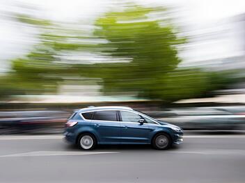 Auto f&auml;hrt innerorts &uuml;ber eine Stra&szlig;e