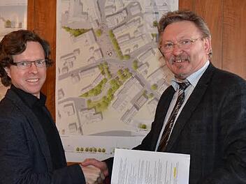 Bürgermeister Hans Pietz (rechts) gratulierte Tilman Latz zum ersten Preis beim Architektenwettbewerb "Neugestaltung Ortsmitte Rothenkirchen". Im Hintergrund rechts der Planentwurf. Foto: K.-H. Hofmann