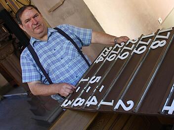 Mesner Hans Welmann beim Einstecken der Liedernummern: Sieben solcher Tafeln hängen in der Erlöserkirche und müssen für jeden Gottesdienst bestückt werden. Fotos: Ralf Ruppert