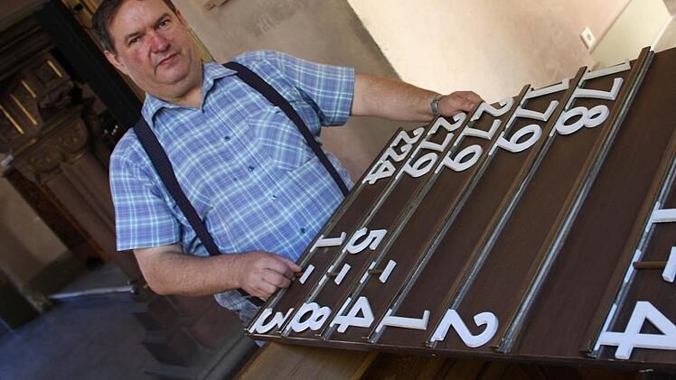 Mesner Hans Welmann beim Einstecken der Liedernummern: Sieben solcher Tafeln hängen in der Erlöserkirche und müssen für jeden Gottesdienst bestückt werden. Fotos: Ralf Ruppert