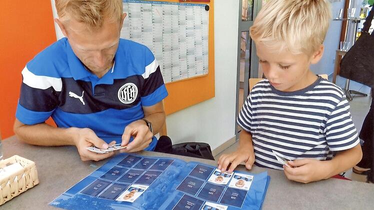 Fußballer Marco Müller und ein junger Sammler sichten die Bilder, die sie noch gut gebrauchen können.