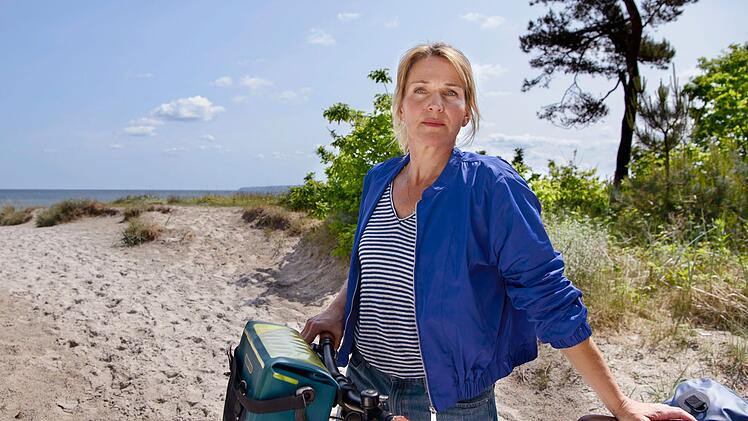 Nach der geplatzten Hochzeit mit Max musste Nora Kaminski (Tanja Wedhorn) erstmal weit weg. Doch zu Beginn des 27. Films "Praxis mit Meerblick - Willkommen zu Hause" kommt sie zur&uuml;ck auf R&uuml;gen.