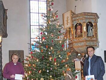 Pfarrer Christof Teille (links) und Bürgermeister Jörg Neubauer laden zum Gemeinschaftssingen an Heiligabend ein. Sie stehen vor dem geschmückten Weihnachtsbaum und der Krippe, die von Mesnerin Margit Redwitz mit ihrem Team in der Dreieinigkeitskirche Weißenbrunn aufgestellt wurden.  Foto: K.- H. Hofmann