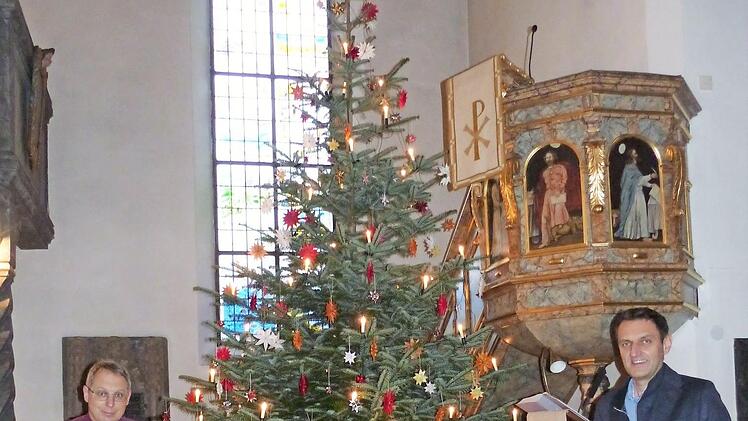 Pfarrer Christof Teille (links) und Bürgermeister Jörg Neubauer laden zum Gemeinschaftssingen an Heiligabend ein. Sie stehen vor dem geschmückten Weihnachtsbaum und der Krippe, die von Mesnerin Margit Redwitz mit ihrem Team in der Dreieinigkeitskirche Weißenbrunn aufgestellt wurden.  Foto: K.- H. Hofmann