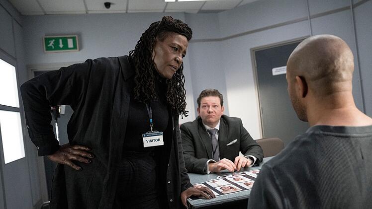 Ermittlerin Ellis (Sharon D Clarke) führt ein Verhör,  misstrauisch beobachtet vom örtlichen Polizei-Verantwortlichen DCI James Belmont (Chris Reilly, Mitte).