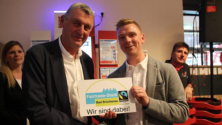 2. Bürgermeister Jürgen Pfister überreicht Sebastian Hauke das Schild. Es weist darauf hin, dass im neuen Markt Produkte aus fairem Handel angeboten werden. Foto: Ulrike Müller
