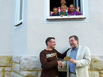 Hans-Heinrich Eidt (rechts) überreicht die Sanierungsmedaille von Stadtbild Coburg an Thorsten Kotschy. Darüber freuen sich auch Rosalie, Katrin, Veit und Johanna Kotschy (oben von links). Foto: Doris Weidner