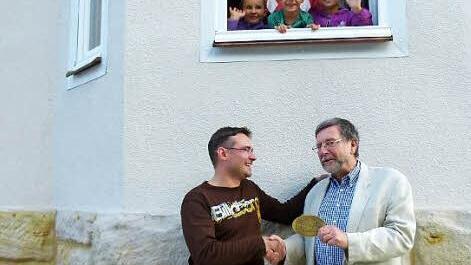 Hans-Heinrich Eidt (rechts) überreicht die Sanierungsmedaille von Stadtbild Coburg an Thorsten Kotschy. Darüber freuen sich auch Rosalie, Katrin, Veit und Johanna Kotschy (oben von links). Foto: Doris Weidner