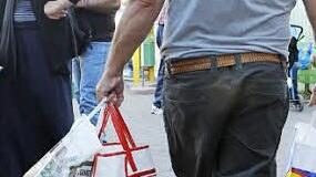Schwer bepackt mit Lebensmitteln geht dieser Mann weg, während andere noch draußen warten, um an die Reihe zu kommen.