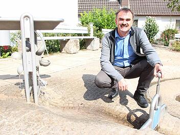 Bürgermeister Harald Hofmann am Brunnen auf dem Henneberger Platz. Die Gemeinde hatte hier ein altes Haus erworben, abgerissen und zu dem offenen Platz umgestaltet. Foto: Benedikt Borst