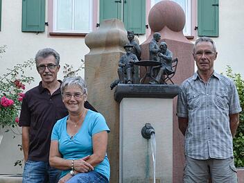 Vor dem Dorfbrunnen haben sich Schriftführer Wolfgang Mandery (von links), Vorsitzende Herta Müller und Reinholf Gabel (Spartenleiter Gartenbau) vom Heimat- und Wanderverein Aschach aufgestellt. Sie bereiten gerade das 50-jährige Vereinsjubiläum vor. Foto: Björn Hein