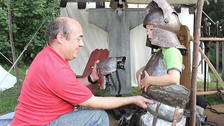 "Ich will ein Ritter werden", scheint der kleine Daniel (4) aus Haßfurt zu sagen. Wie gut, dass Papa Detlef Raudszus tatkräftig beim Anlegen der Rüstung hilft.