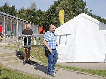 Auf dem Weg an Absperrgittern und einem Verpflegungszelt vorbei führt der Weg von DJK-Elektriker Hans Pfautsch (vorne) und Fußball-Abteilungsleiter Rainer Schmidt, die auch am Donnerstag auf dem Vereinsgelände in Wildensorg werkelten. Foto: Peter Seidel