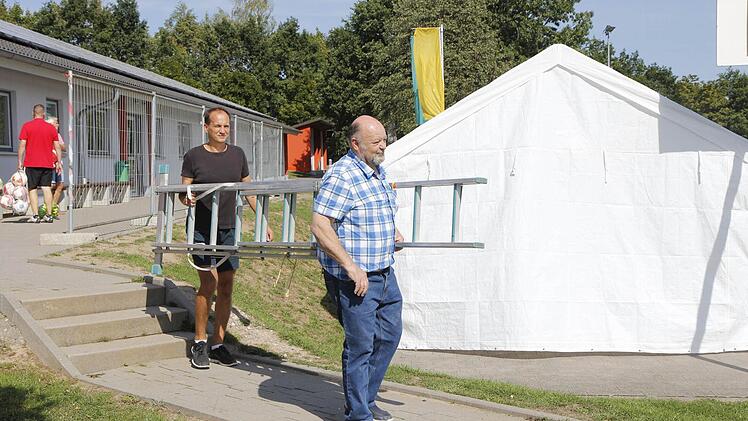 Auf dem Weg an Absperrgittern und einem Verpflegungszelt vorbei führt der Weg von DJK-Elektriker Hans Pfautsch (vorne) und Fußball-Abteilungsleiter Rainer Schmidt, die auch am Donnerstag auf dem Vereinsgelände in Wildensorg werkelten. Foto: Peter Seidel