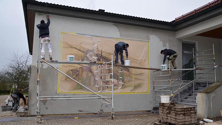 Mitarbeiter der Firma Gessner sind hier dabei, die Wand am Eingang neu zu verputzen. Vorher haben sie jedoch das Wandgemälde von Gerald Kriedner abgeklebt, um es zu schützen. Foto: Kathrin Kupka-Hahn