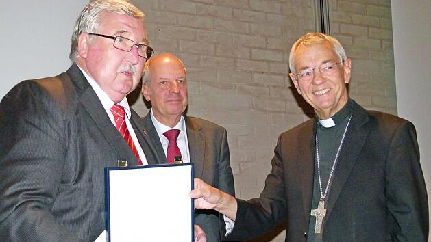 Gerhard Öhlein (links) erhielt die höchste Auszeichnung des Deutschen Caritasverbandes, den Silbernen Brotteller. Überreicht wurde dieser von Vizepräsident Heinz-Josef Kessmann mit Erzbischof Ludwig Schick. Foto: Marion Krüger Hundrup