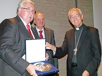 Gerhard Öhlein (links) erhielt die höchste Auszeichnung des Deutschen Caritasverbandes, den Silbernen Brotteller. Überreicht wurde dieser von Vizepräsident Heinz-Josef Kessmann mit Erzbischof Ludwig Schick. Foto: Marion Krüger Hundrup