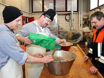 Die zwei Metzger (von li) Gerald Klotz und Harald Kraus rühren unter den kritischen Blicken des Kommandanten und Hilfsmetzgers Jürgen Hörrlein die Leberwurstfüllung an. Fotos: Johanna Blum