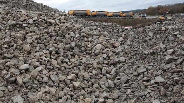 An der ICE-Baustelle bei Kersbach werden die Schotterberge zwischengelagert, bis die Lastwagen (Im Hintergrund) das Material zur neuen Trasse fahren. Foto: Josef Hofbauer