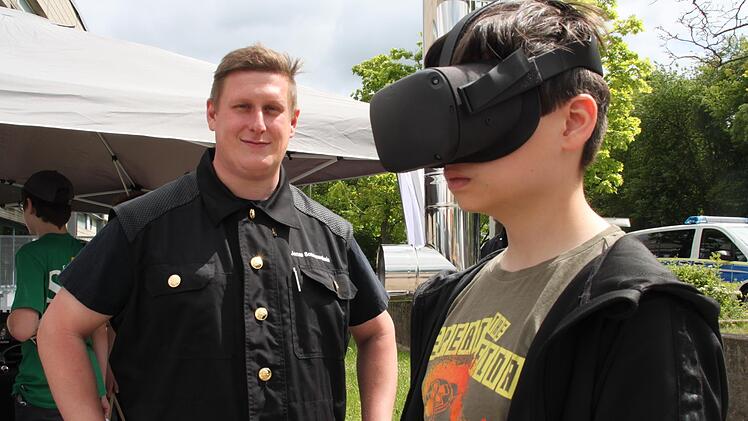Mit Hilfe einer Virtual-Reality-Brille schaut Dominik Lindner Schornsteinfegern bei ihrer Arbeit auf dem Dach über die Schulter. Mit im Bild Bezirkskaminkehrermeister Jonas Sonnenschein aus Stadtsteinach. Foto: Stephan Stöckel