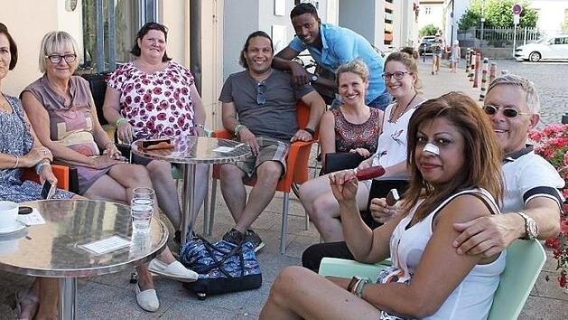 Besucher des MGH-Sprachcaf&eacute;s genie&szlig;en das sonnige Wetter in gem&uuml;tlicher Runde vor dem Mehrgenerationenhaus in Ha&szlig;furt. Foto: Johanna Ott